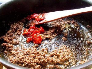 Fry the Paste Push the meat to the side (or leave it mixed in). Add the minced Doubanjiang (40g) to the oil.