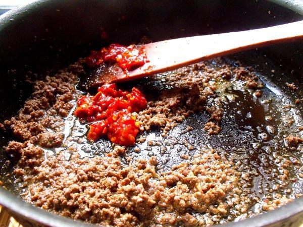 Fry the Paste Push the meat to the side (or leave it mixed in). Add the minced Doubanjiang (40g) to the oil.