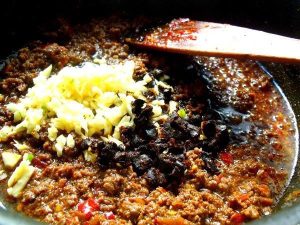 Aromatics Add the chili powder, minced garlic, and crushed fermented black beans (Douchi).
