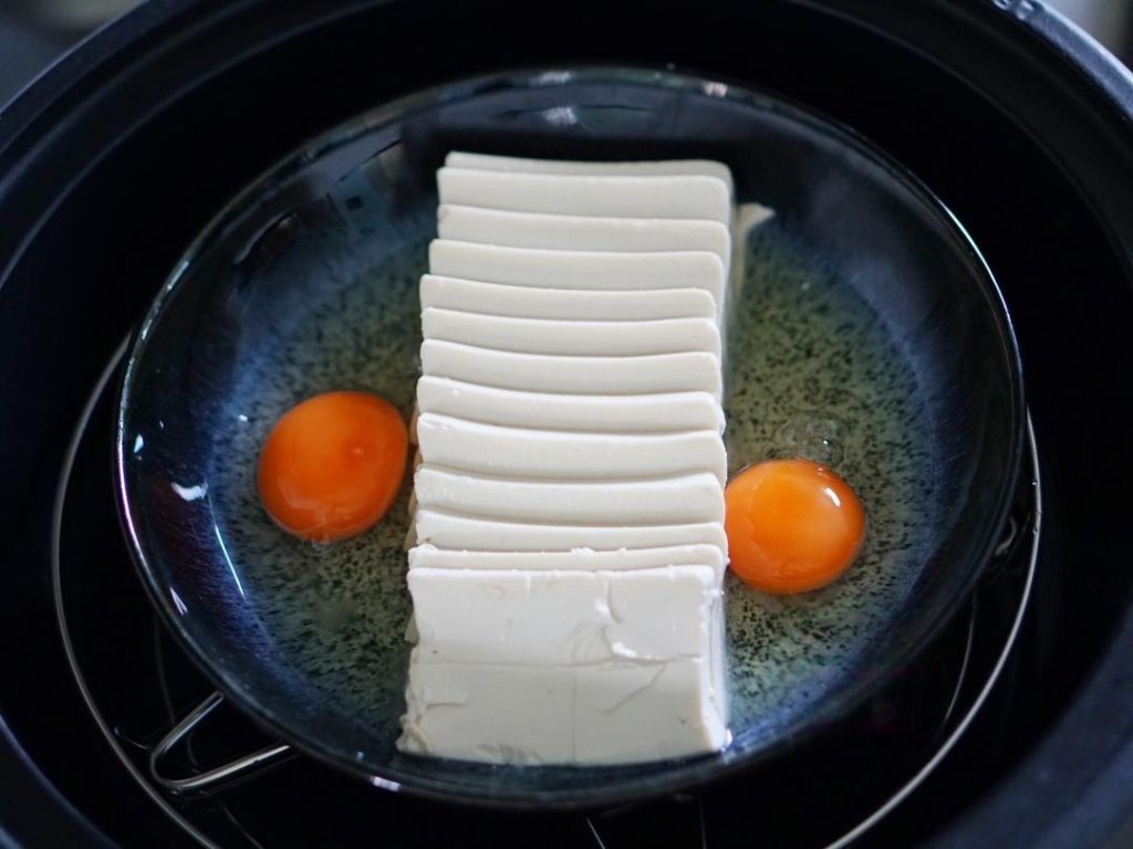 Add Eggs: Crack the eggs onto the plate on either side of the tofu rows.