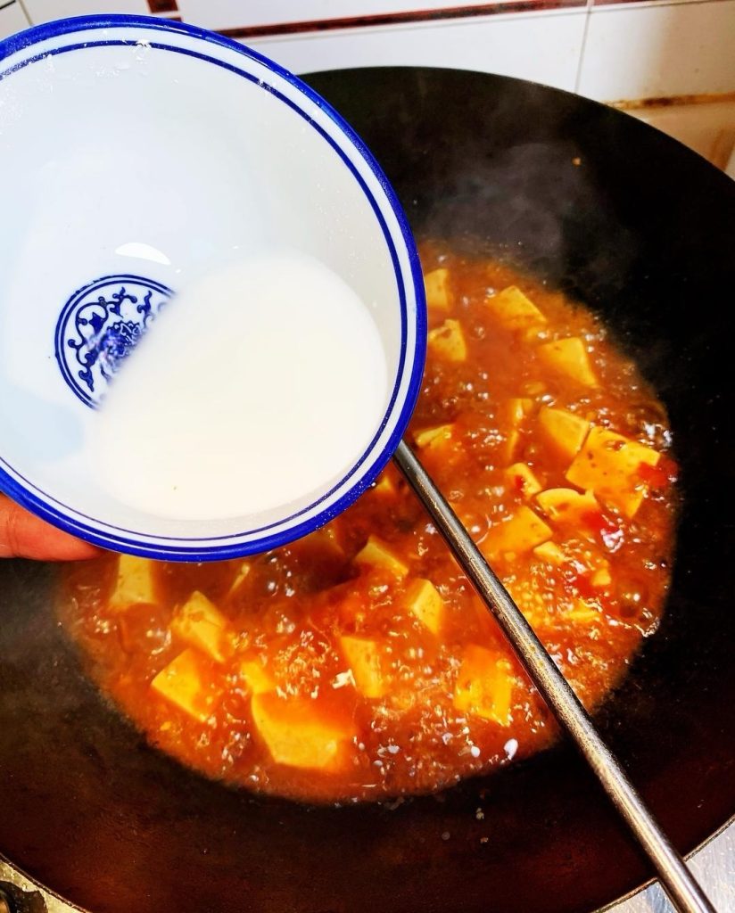 The Three-Stage Thickening (Important!) Remove the lid. Turn the heat up slightly. We will add the starch water in three separate batches