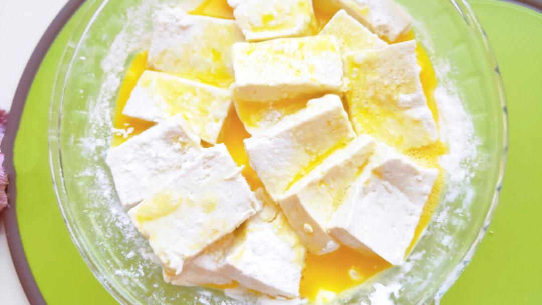 Dip the cornstarched tofu slabs into the beaten egg.