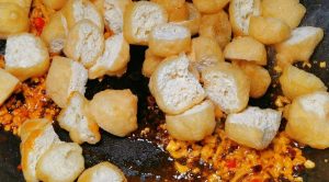 Add the halved tofu puffs and stir-fry until