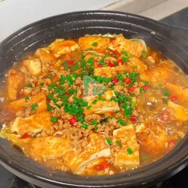 Golden tofu stacked in a clay pot under savory pork mince