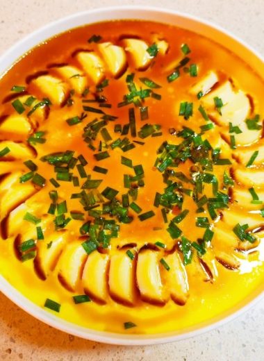 Rounds of egg tofu in a steamed milk custard with scallion
