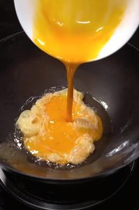 In the leftover oil, pour in the beaten egg